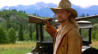 Legends of the Fall Screenshot - Brad building holding a rifle with the Alberta Rocky Mountains as backdrop